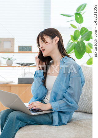 一位時尚的年輕亞洲女性一邊使用電腦,一邊用智慧型手機通話 一位時尚的年輕亞洲女性一邊使用電腦,一邊用智慧型手機通話 143231058