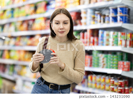 Girl in supermarket search and select product tin can Girl in supermarket search and select product tin can 143231090
