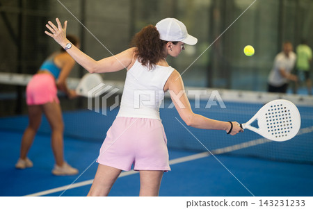 Woman with racket training on outdoor court playing padel game and hitting ball Woman with racket training on outdoor court playing padel game and hitting ball 143231233