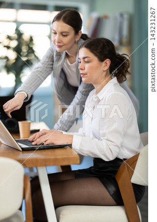 Young girl helping colleague with tasks on laptop Young girl helping colleague with tasks on laptop 143231267