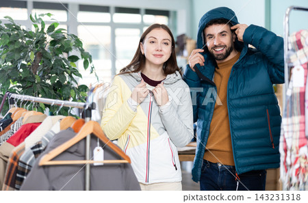 Couple trying on jackets in a clothing store Couple trying on jackets in a clothing store 143231318