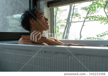 A man in his 40s closes his eyes in the bathtub and massages his shoulders and neck. A relaxing bath time to refresh mind and body. A man in his 40s closes his eyes in the bathtub and massages his shoulders and neck. A relaxing bath time to refresh mind and body. 143231408