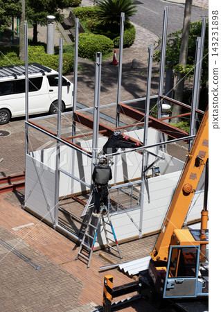 身穿空調工作服的建築工人和鷹架工人在建築工地搭建臨時辦公室。 身穿空調工作服的建築工人和鷹架工人在建築工地搭建臨時辦公室。 143231898