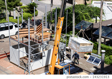 身穿空調工作服的建築工人和鷹架工人在建築工地搭建臨時辦公室。 身穿空調工作服的建築工人和鷹架工人在建築工地搭建臨時辦公室。 143231913
