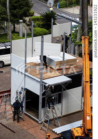 身穿空調工作服的建築工人和鷹架工人在建築工地搭建臨時辦公室。 143231922