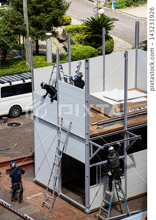 身穿空調工作服的建築工人和鷹架工人在建築工地搭建臨時辦公室。 身穿空調工作服的建築工人和鷹架工人在建築工地搭建臨時辦公室。 143231926