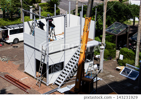 身穿空調工作服的建築工人和鷹架工人在建築工地搭建臨時辦公室。 身穿空調工作服的建築工人和鷹架工人在建築工地搭建臨時辦公室。 143231929
