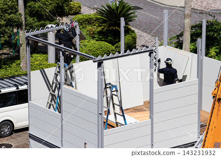 身穿空調工作服的建築工人和鷹架工人在建築工地搭建臨時辦公室。 身穿空調工作服的建築工人和鷹架工人在建築工地搭建臨時辦公室。 143231932