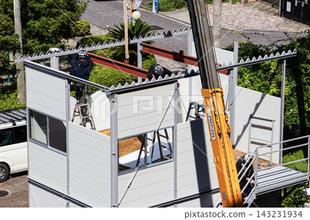 身穿空調工作服的建築工人和鷹架工人在建築工地搭建臨時辦公室。 身穿空調工作服的建築工人和鷹架工人在建築工地搭建臨時辦公室。 143231934