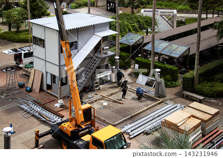 身穿空調工作服的建築工人和鷹架工人在建築工地搭建臨時辦公室。 身穿空調工作服的建築工人和鷹架工人在建築工地搭建臨時辦公室。 143231946