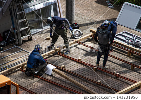 身穿空調工作服的建築工人和鷹架工人在建築工地搭建臨時辦公室。 身穿空調工作服的建築工人和鷹架工人在建築工地搭建臨時辦公室。 143231950