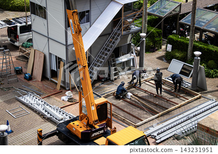 身穿空調工作服的建築工人和鷹架工人在建築工地搭建臨時辦公室。 身穿空調工作服的建築工人和鷹架工人在建築工地搭建臨時辦公室。 143231951