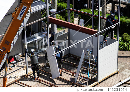 身穿空調工作服的建築工人和鷹架工人在建築工地搭建臨時辦公室。 身穿空調工作服的建築工人和鷹架工人在建築工地搭建臨時辦公室。 143231954