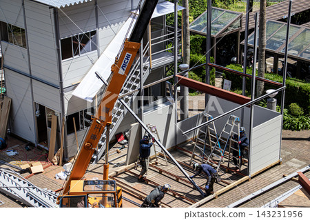 身穿空調工作服的建築工人和鷹架工人在建築工地搭建臨時辦公室。 身穿空調工作服的建築工人和鷹架工人在建築工地搭建臨時辦公室。 143231956