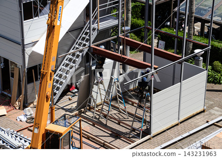 身穿空調工作服的建築工人和鷹架工人在建築工地搭建臨時辦公室。 身穿空調工作服的建築工人和鷹架工人在建築工地搭建臨時辦公室。 143231963