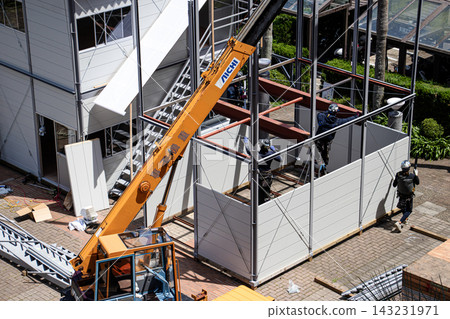 身穿空調工作服的建築工人和鷹架工人在建築工地搭建臨時辦公室。 身穿空調工作服的建築工人和鷹架工人在建築工地搭建臨時辦公室。 143231971