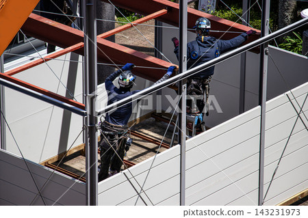 身穿空調工作服的建築工人和鷹架工人在建築工地搭建臨時辦公室。 身穿空調工作服的建築工人和鷹架工人在建築工地搭建臨時辦公室。 143231973