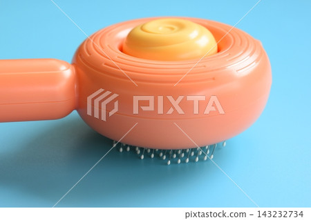 pastel orange comb on blue background, hair brush for pet 143232734