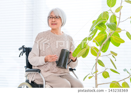 一位坐在輪椅上的老婦人喜歡照顧室內植物。園藝是她健康退休生活的核心。 143238369