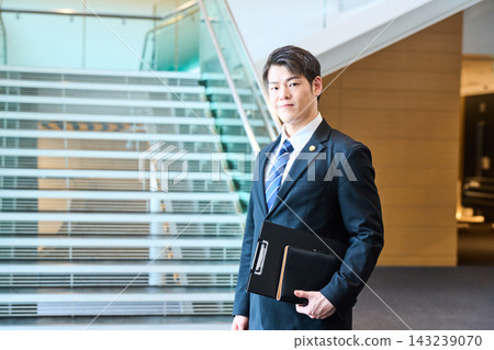 一位面帶自信的年輕日本專業人士站在辦公大樓的階梯前。 一位面帶自信的年輕日本專業人士站在辦公大樓的階梯前。 143239070