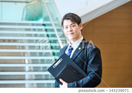 一位面帶自信的年輕日本專業人士站在辦公大樓的階梯前。 一位面帶自信的年輕日本專業人士站在辦公大樓的階梯前。 143239071