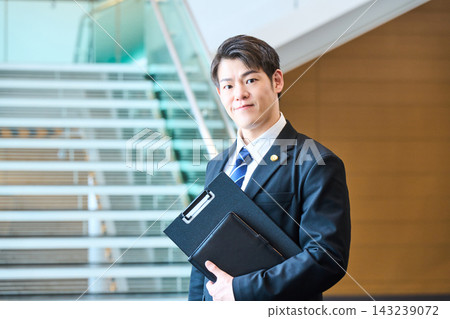一位面帶自信的年輕日本專業人士站在辦公大樓的階梯前。 一位面帶自信的年輕日本專業人士站在辦公大樓的階梯前。 143239072