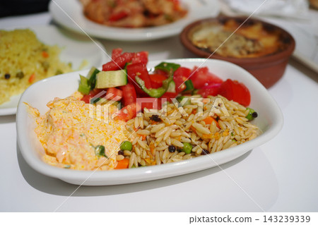 Dish served with rice, salad, and creamy sauce on a plate at a dining table 143239339