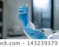 Scientist gloved hand holding glass test tube with blue liquid in laboratory setting 143239379