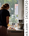 Woman slicing plums for a cake by the kitchen window 143239720