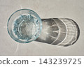 Glass of water in sunlight with shadow on countertop 143239725