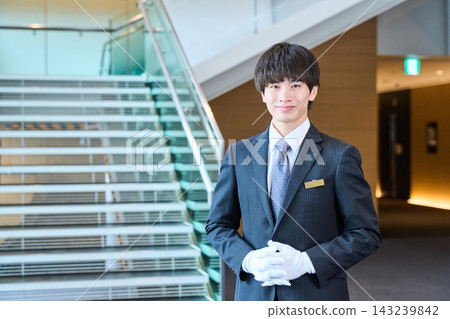 男性工作人員微笑著迎接客人,並在大廳和樓梯頂端提供協助。 男性工作人員微笑著迎接客人,並在大廳和樓梯頂端提供協助。 143239842