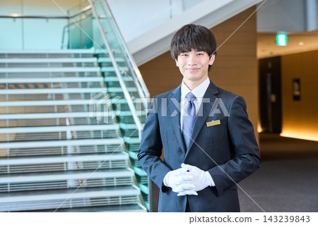 男性工作人員微笑著迎接客人,並在大廳和樓梯頂端提供協助。 男性工作人員微笑著迎接客人,並在大廳和樓梯頂端提供協助。 143239843