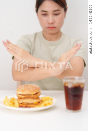 Unhappy woman showing Rejecting and refusing with Juicy beef burger, potato chips and carbonated Soft drinks. Unhealthy, High calorie, Fast food craving, Obesity, diet, weight loss and junk food Unhappy woman showing Rejecting and refusing with Juicy beef burger, potato chips and carbonated Soft drinks. Unhealthy, High calorie, Fast food craving, Obesity, diet, weight loss and junk food 143240192