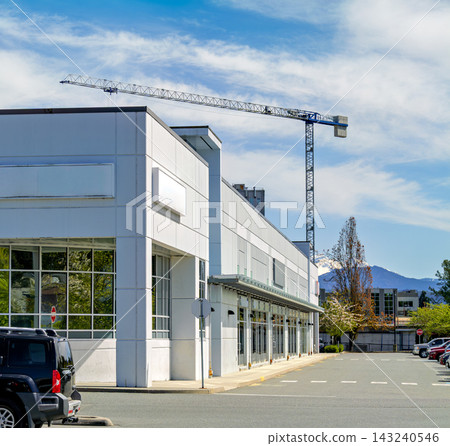 Modern commercial building with parking lot and construction crane Modern commercial building with parking lot and construction crane 143240546