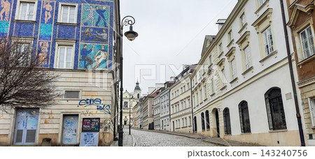 Cobblestone street in Warsaw Old Town with colorful mosaic mural on a building facade - Warsaw, Poland - January 26, 2023 Cobblestone street in Warsaw Old Town with colorful mosaic mural on a building facade - Warsaw, Poland - January 26, 2023 143240756