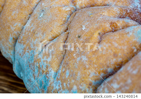 Close-up of light blue mold spreading across the crust of a loaf of bread. Close-up of light blue mold spreading across the crust of a loaf of bread. 143240814