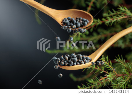 Juniper berries are sprinkled with a wooden spoon. Juniper berries are sprinkled with a wooden spoon. 143243124