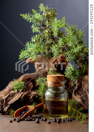 Juniper berry essential oil, berries, and green branches. Juniper berry essential oil, berries, and green branches. 143243129