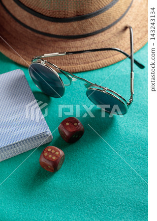 Playing cards, wooden dice, sunglasses and a hat on a green cloth. Playing cards, wooden dice, sunglasses and a hat on a green cloth. 143243134