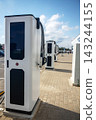 Modern electric vehicle charging stations standing in row on stone paved street at sunny summer daytime 143244155