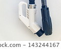 Close up of modern electric vehicle charging plugs hanging on bright white station panel with copy space 143244167