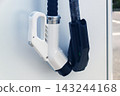 Black and white electric vehicle charging plugs at public outdoor terminal on summer day 143244168