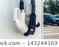 Electric vehicle charging connectors at public outdoor station in sunny parking lot 143244169