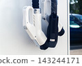 Electric vehicle charging plugs on station wall at public parking lot at sunny summer daytime 143244171