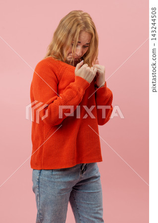 Young woman looking down with a worried expression, feeling timid and unsure, covering her face with clenched fists, embodying concepts of shyness, fear, and apprehension on a pink background Young woman looking down with a worried expression, feeling timid and unsure, covering her face with clenched fists, embodying concepts of shyness, fear, and apprehension on a pink background 143244508