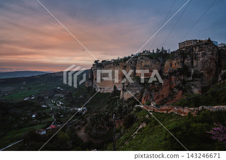 Ronda limestone cliffs and green valley under an orange sunset sky Ronda limestone cliffs and green valley under an orange sunset sky 143246671