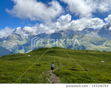 Hikers walking along alpine trail facing Mont Blanc, France Hikers walking along alpine trail facing Mont Blanc, France 143246763