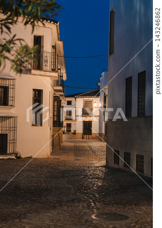 Quiet cobblestone street with whitewashed houses in Ronda old town at blue hour 143246862