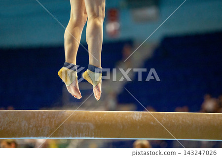 Close up female gymnast jumping above balance beam Close up female gymnast jumping above balance beam 143247026
