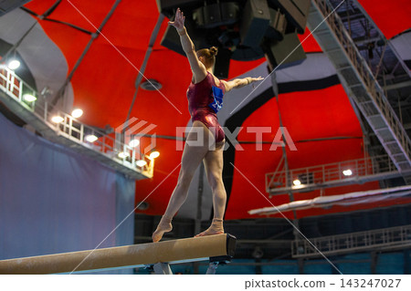 Female gymnast performing routine on balance beam Female gymnast performing routine on balance beam 143247027